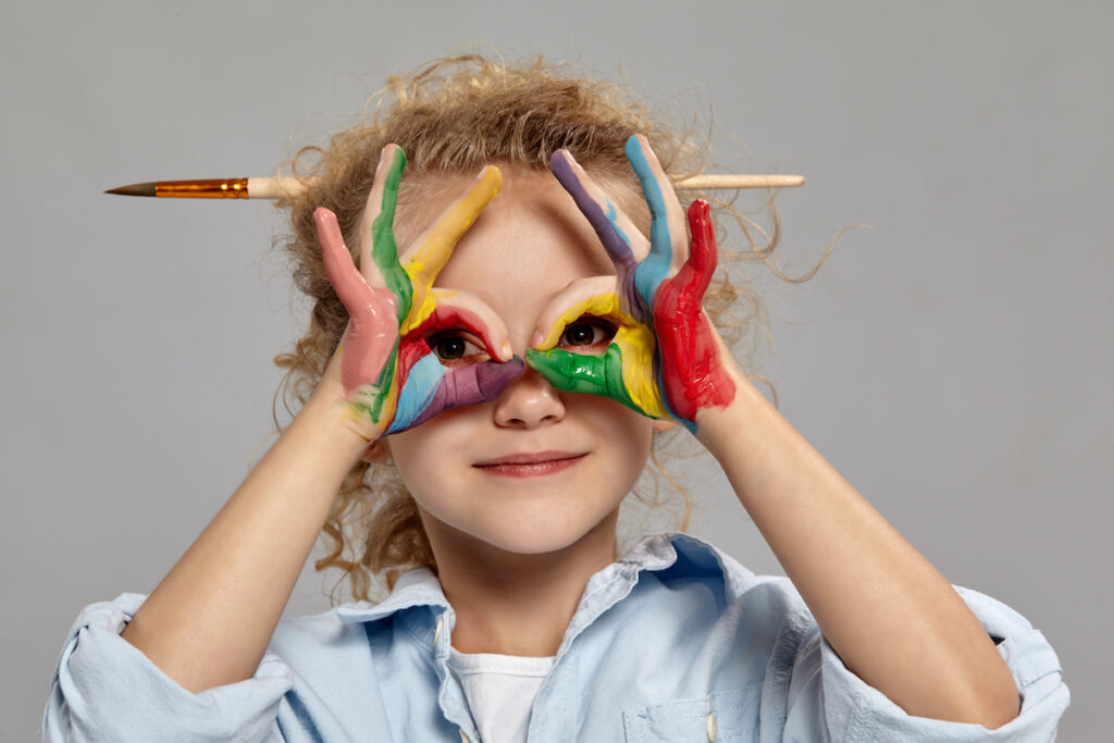 Bambina sorridente che guarda attraverso le mani messe come se fossero degli occhiali