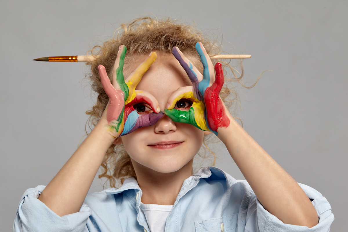 Bambina sorridente che guarda attraverso le mani messe come se fossero degli occhiali
